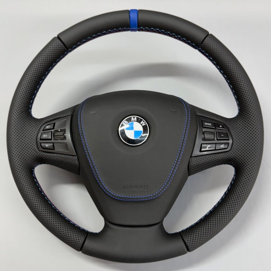 Volan cu airbag îmbrăcat în piele neagră, cu cusătură albastră contrastantă